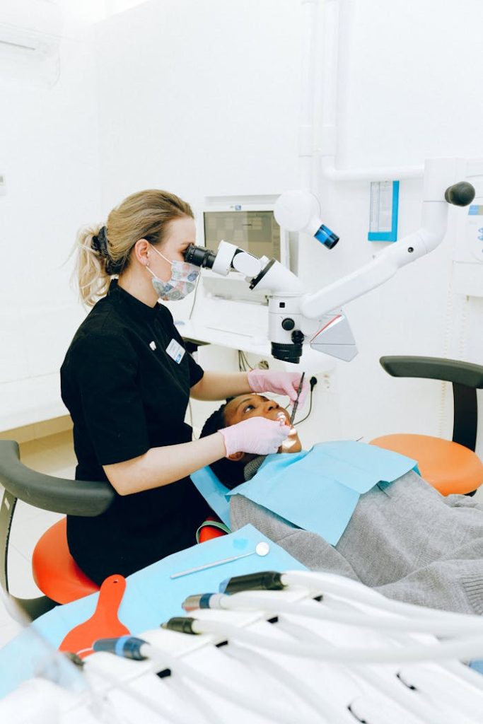 dental-check-up-3845761 Female dentist in clinic examining a patient with modern dental equipment.
